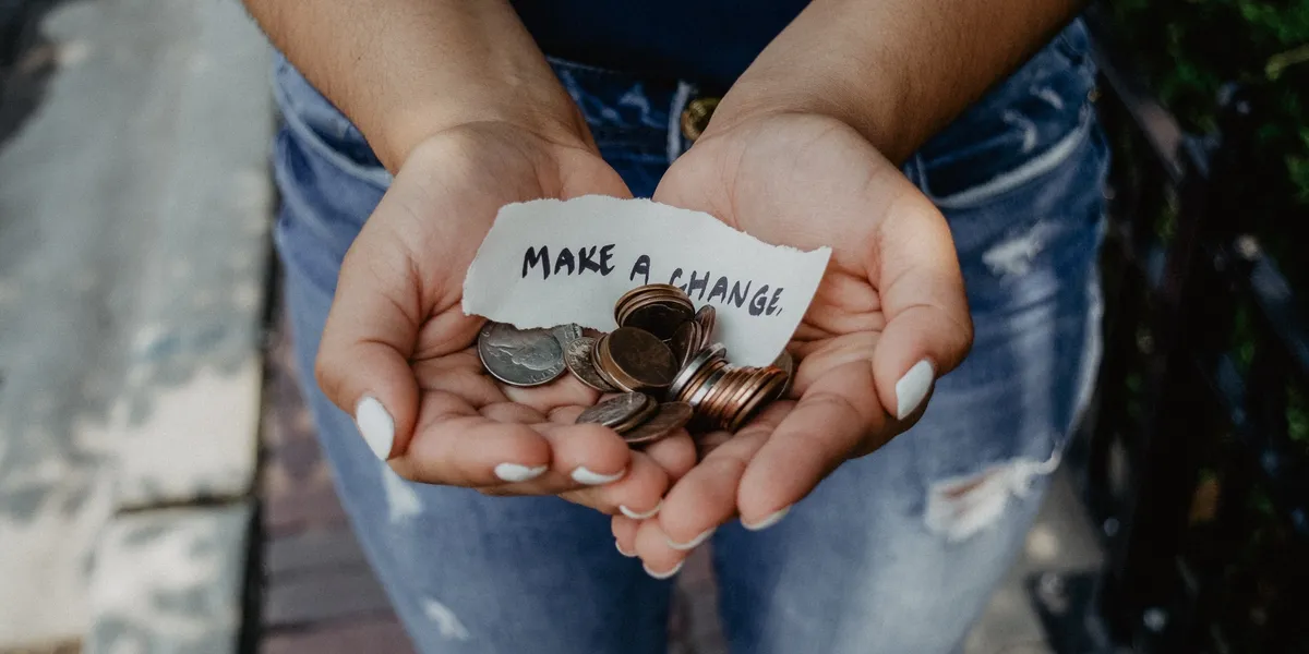 A pair of hands with some coins and loose change.